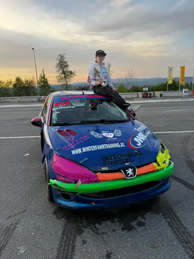 Die Fahrerin mit dem Pokal auf dem Dach ihres Rennwagens nach dem Rennen